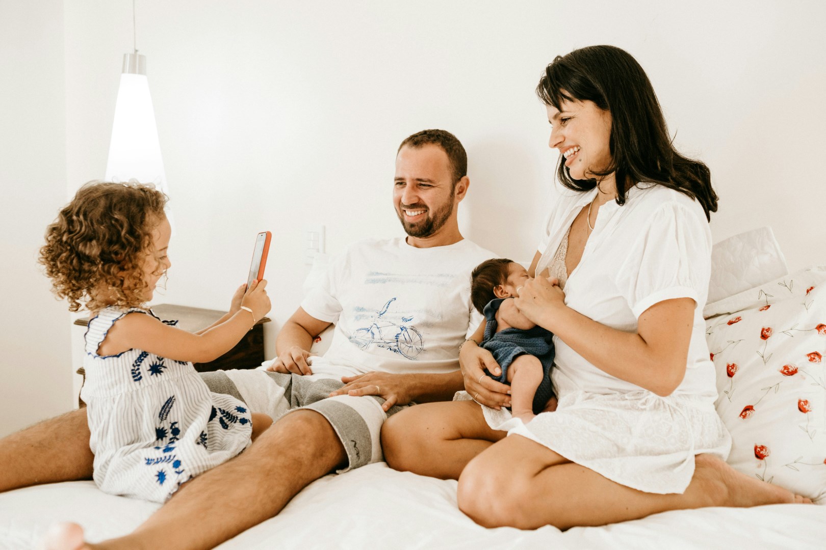 Family happily sitting on bed and taking a photo